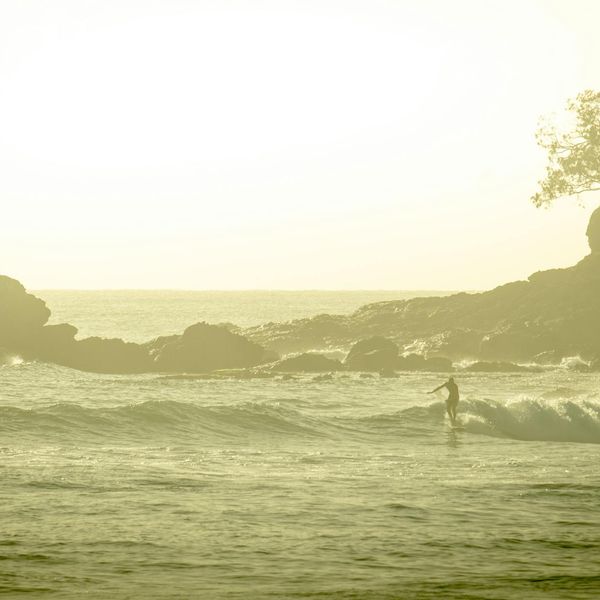 Silhouette of a person meditating against a sunrise with blue hues.